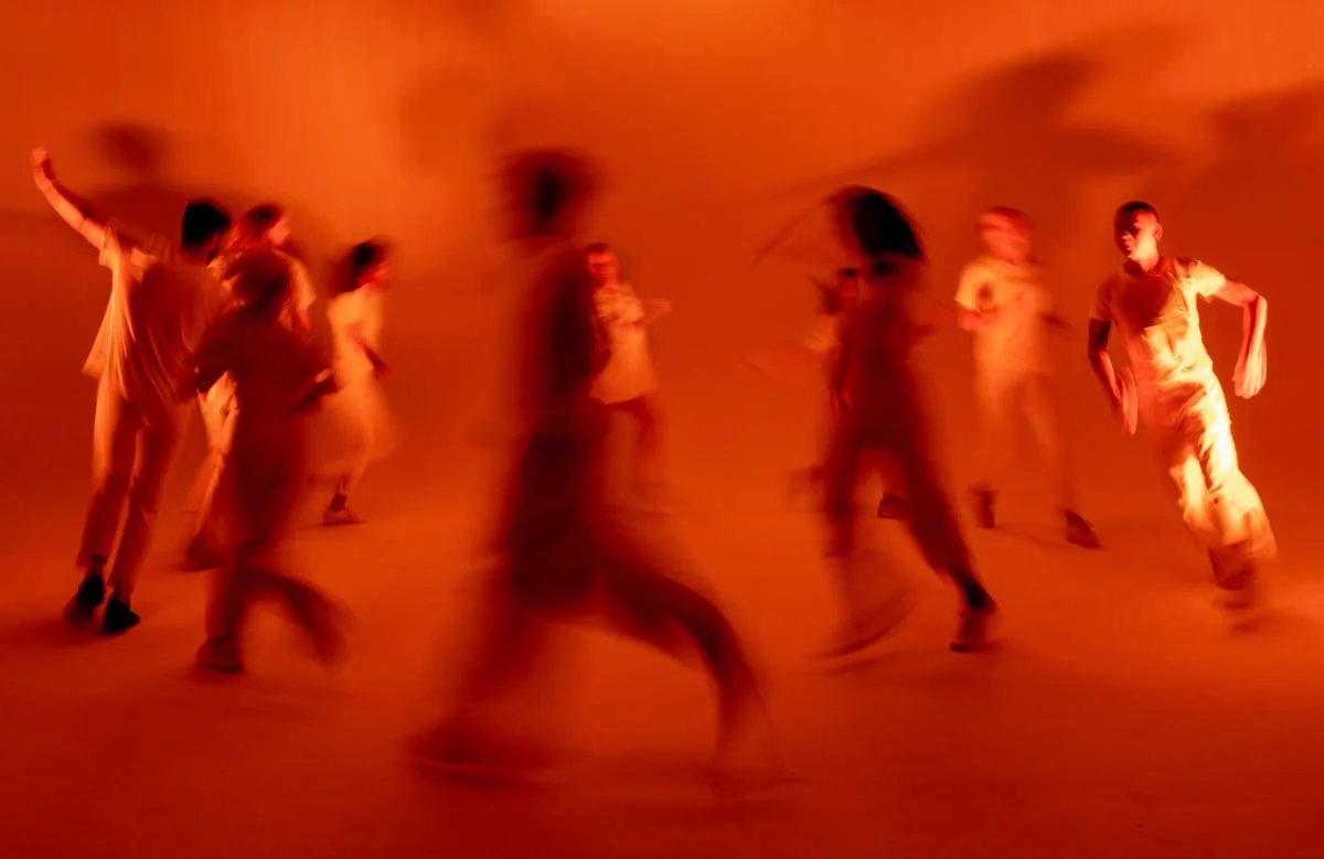 Dancers moving through warm red stage light